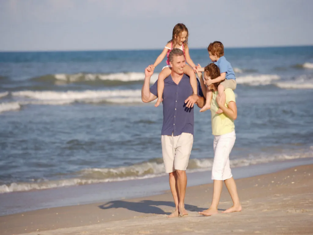 New Buffalo Public Beach and Lakefront Park. Man and wife carrying children on their shoulders while walking on the Public beach
