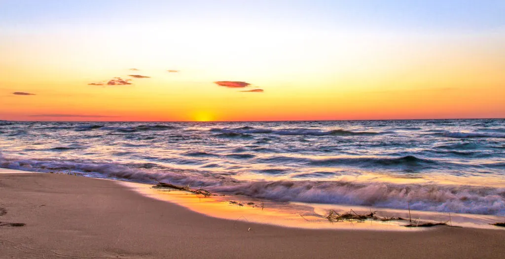 Sunsets are free at the New Buffalo Public Beach and along Lake Michigan. Sun setting over Lake Michigan with waves lapping at the shoreline